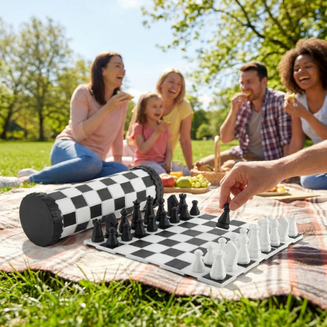 Family playing the VIGOR portable chess set on a picnic blanket in the park